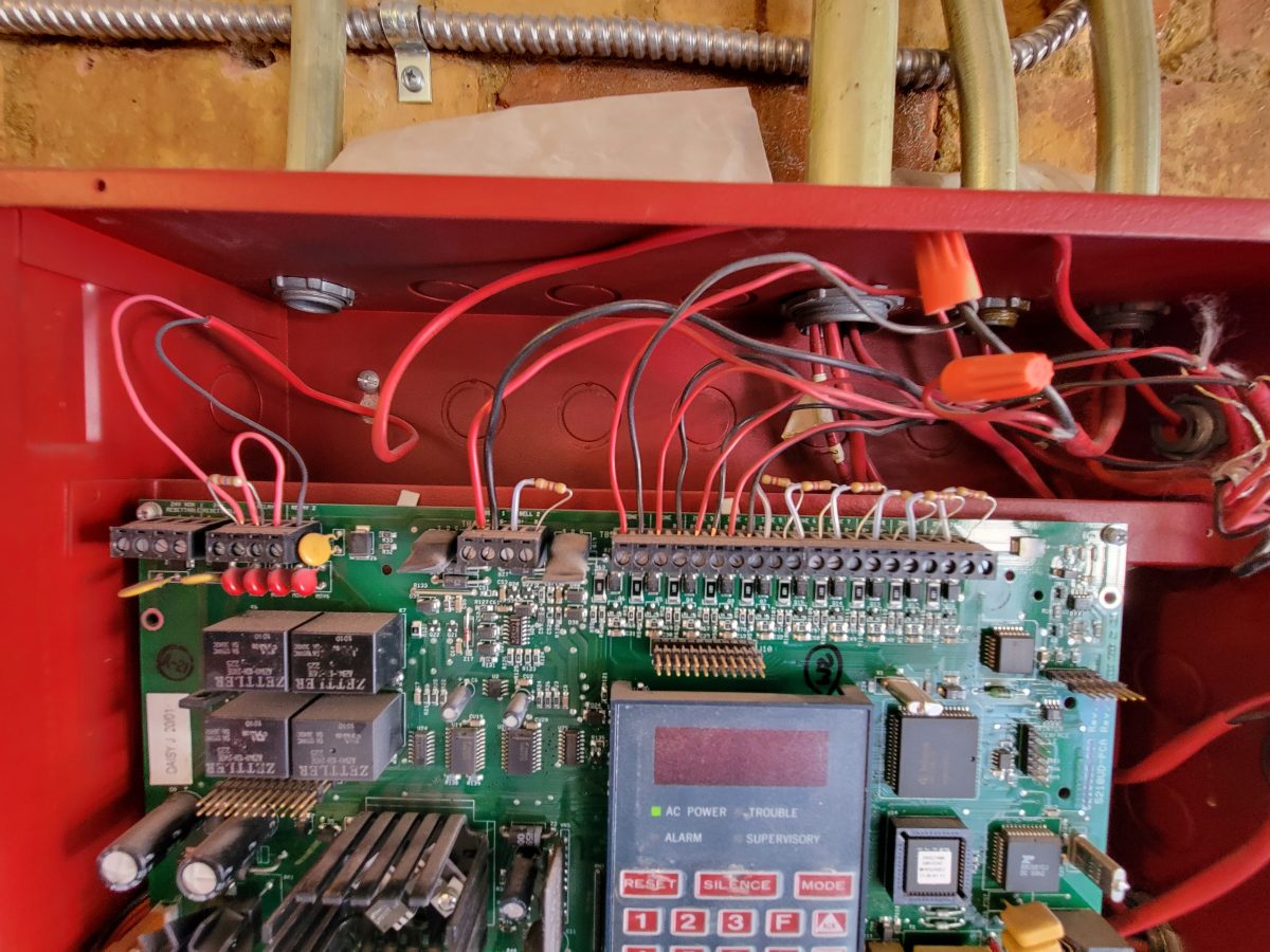The inside of a fire alarm control panel, with field wiring landed on terminal strips and the AC power, trouble, alarm and supervisory indicators visible