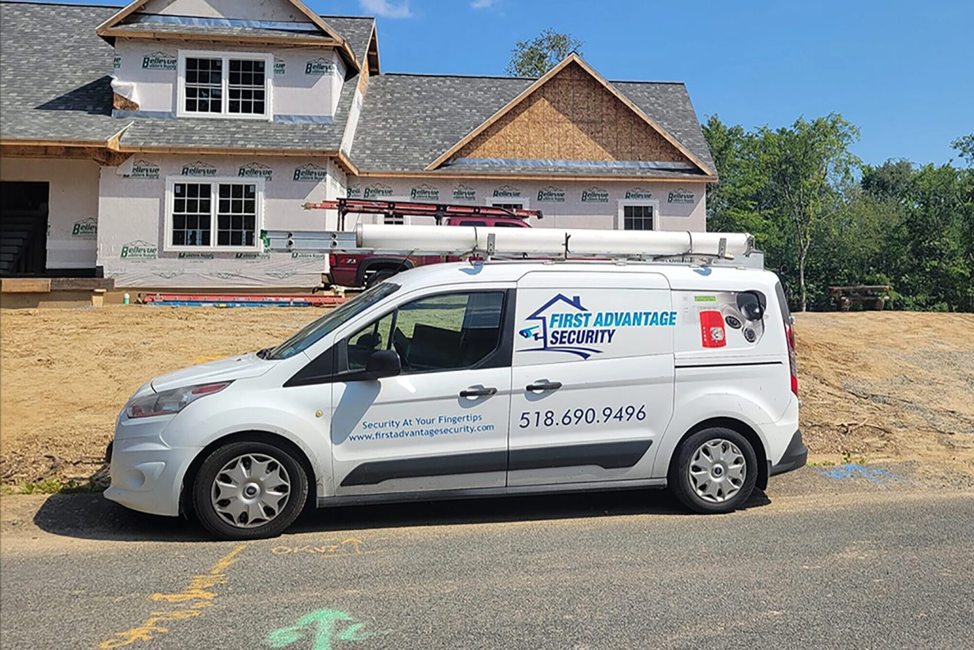 A First Advantage Security van parked at a house under construction, the building still in house wrap with no siding and the lot freshly graded